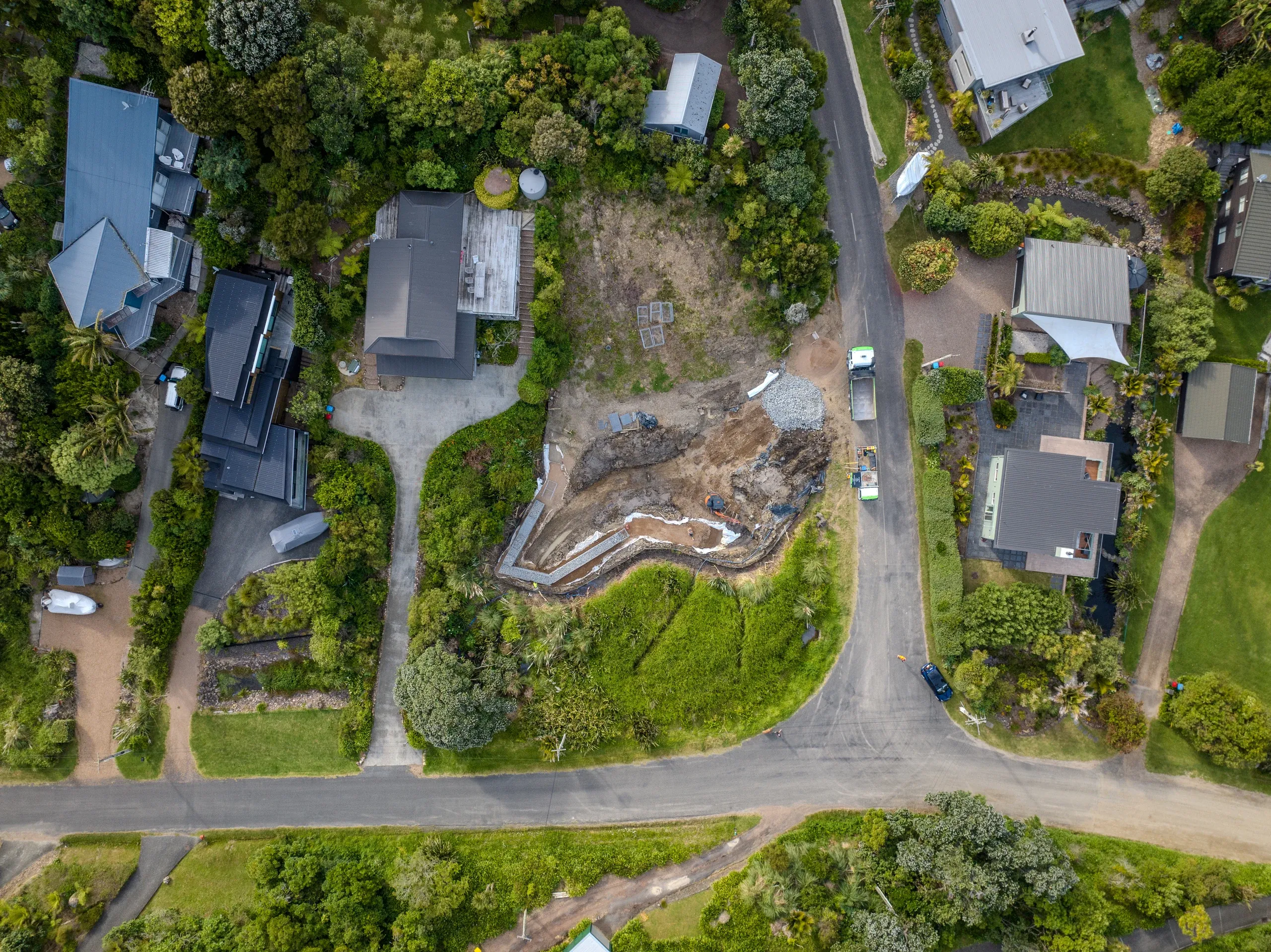 Aerial view straight down over the site mid-build, the terrace cut and retaining line clearly visible.