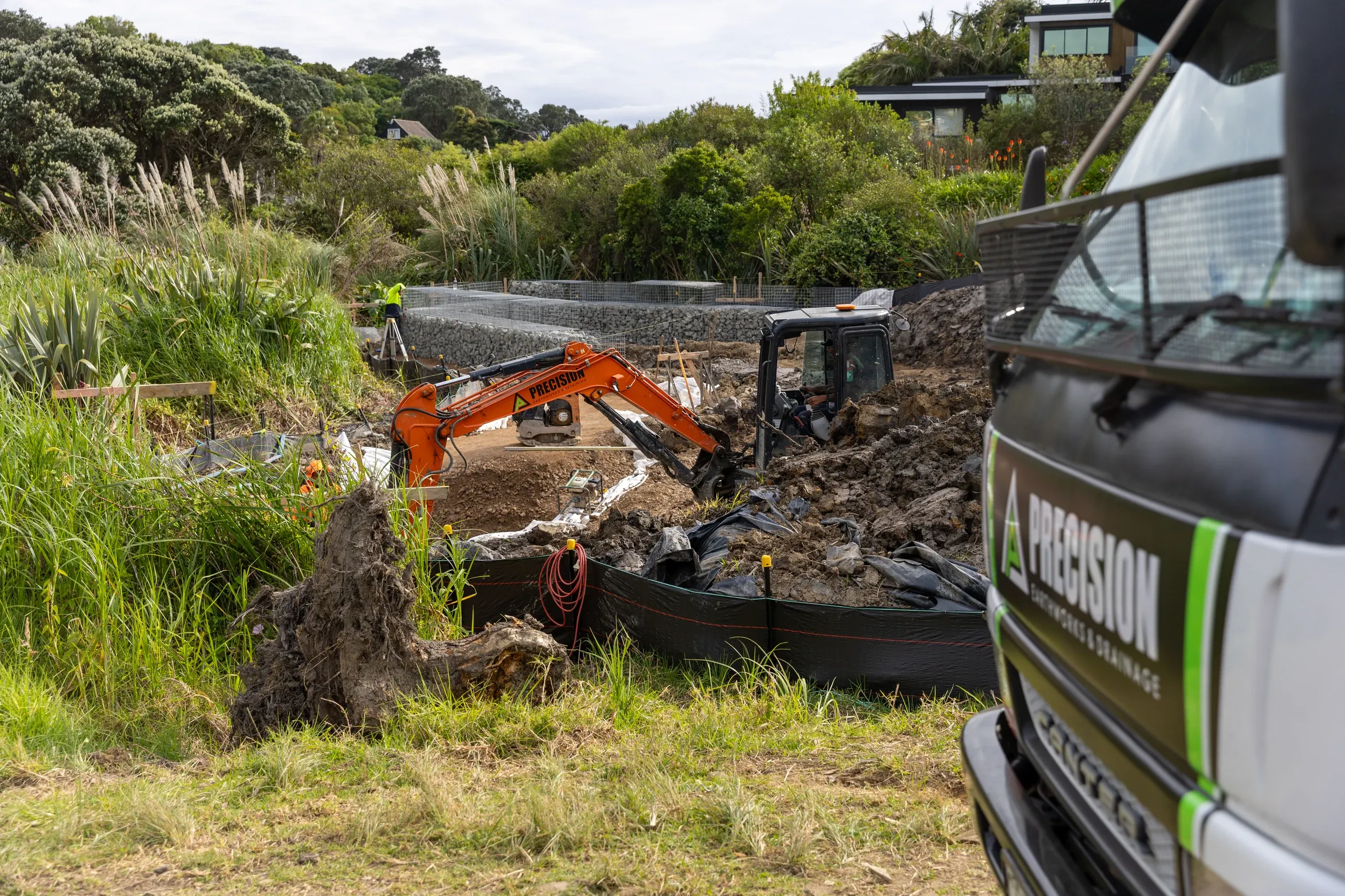 A Precision drainage truck on site while the excavator works the cut behind it.