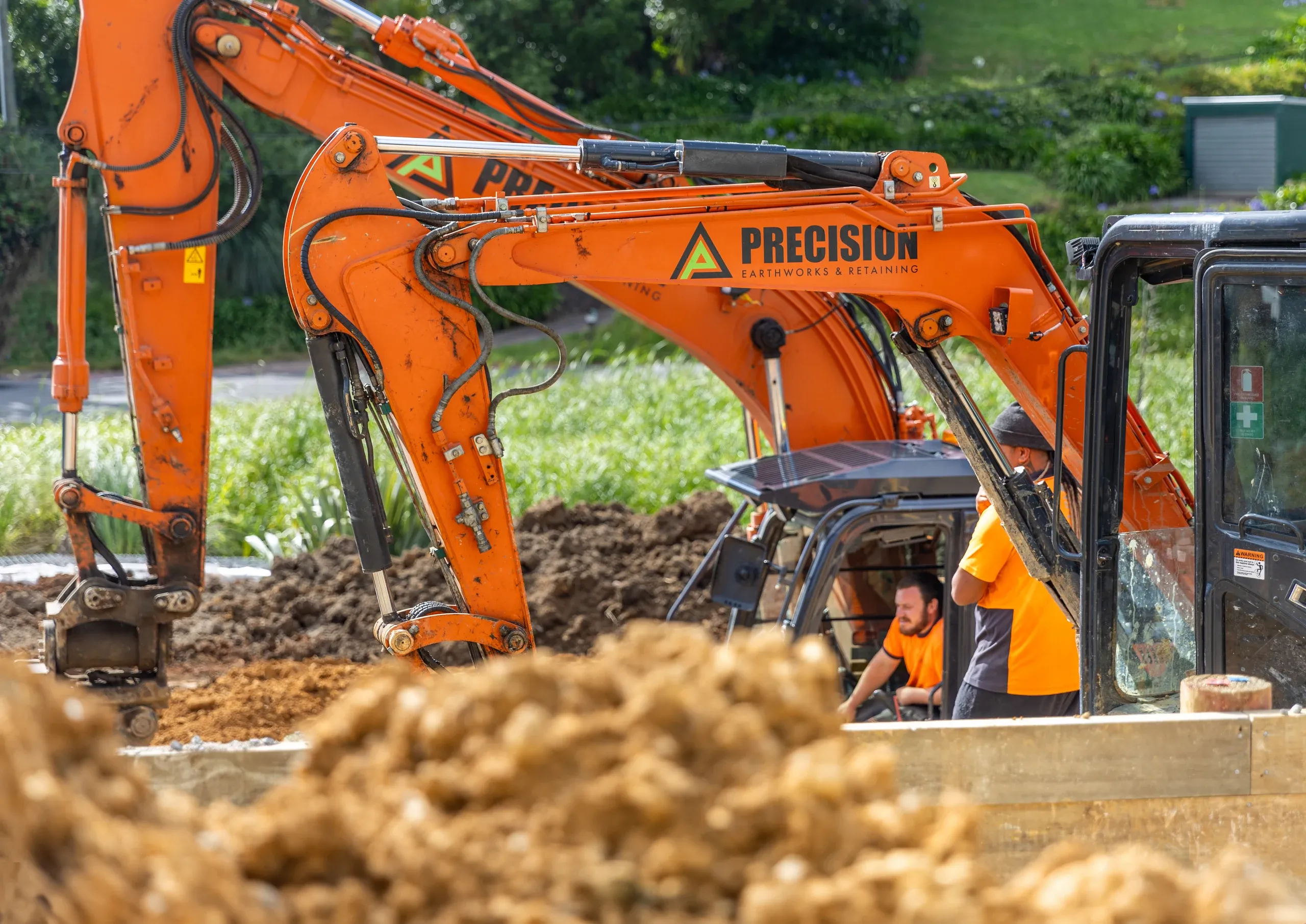 The excavator boom swung across the cut, the operator working spoil from the terrace face.