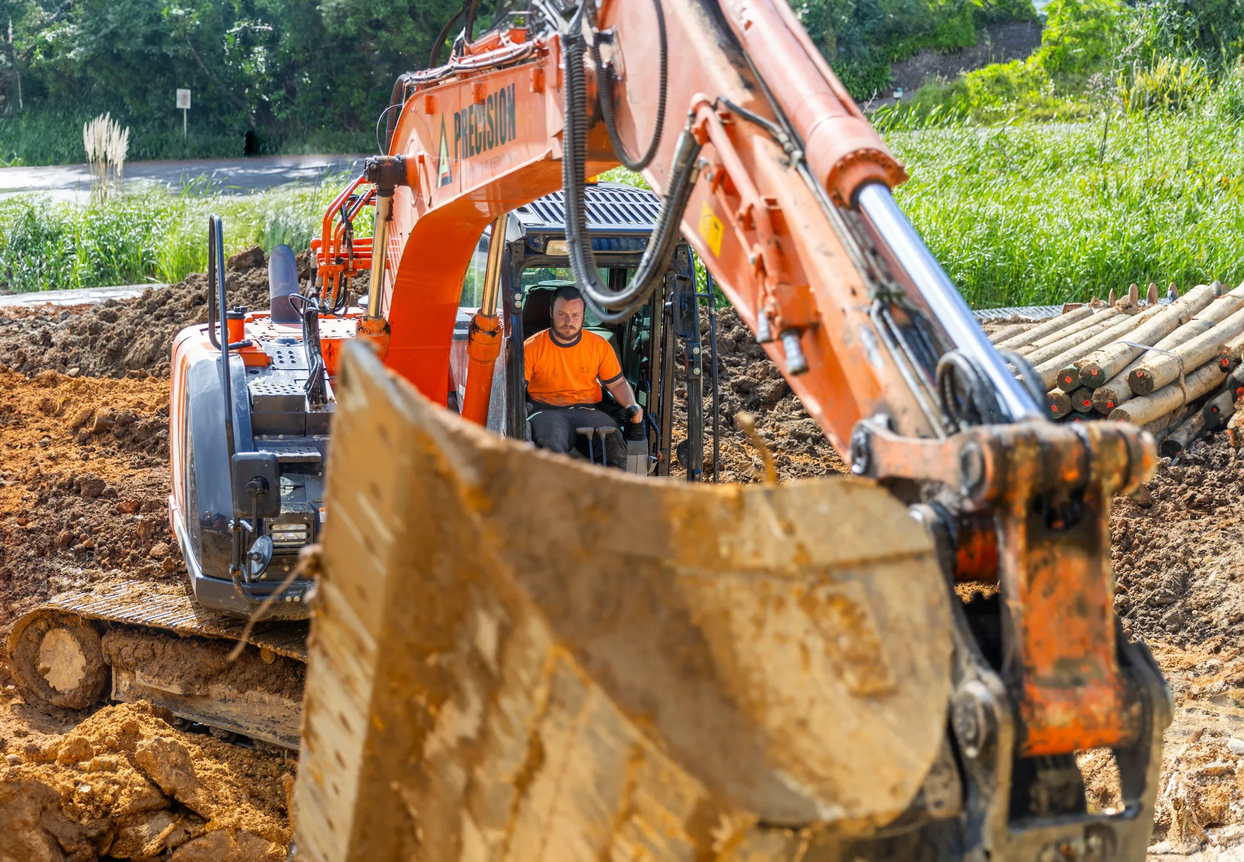 Bucket in the foreground and retaining poles stacked on site, ready for the next section of wall.