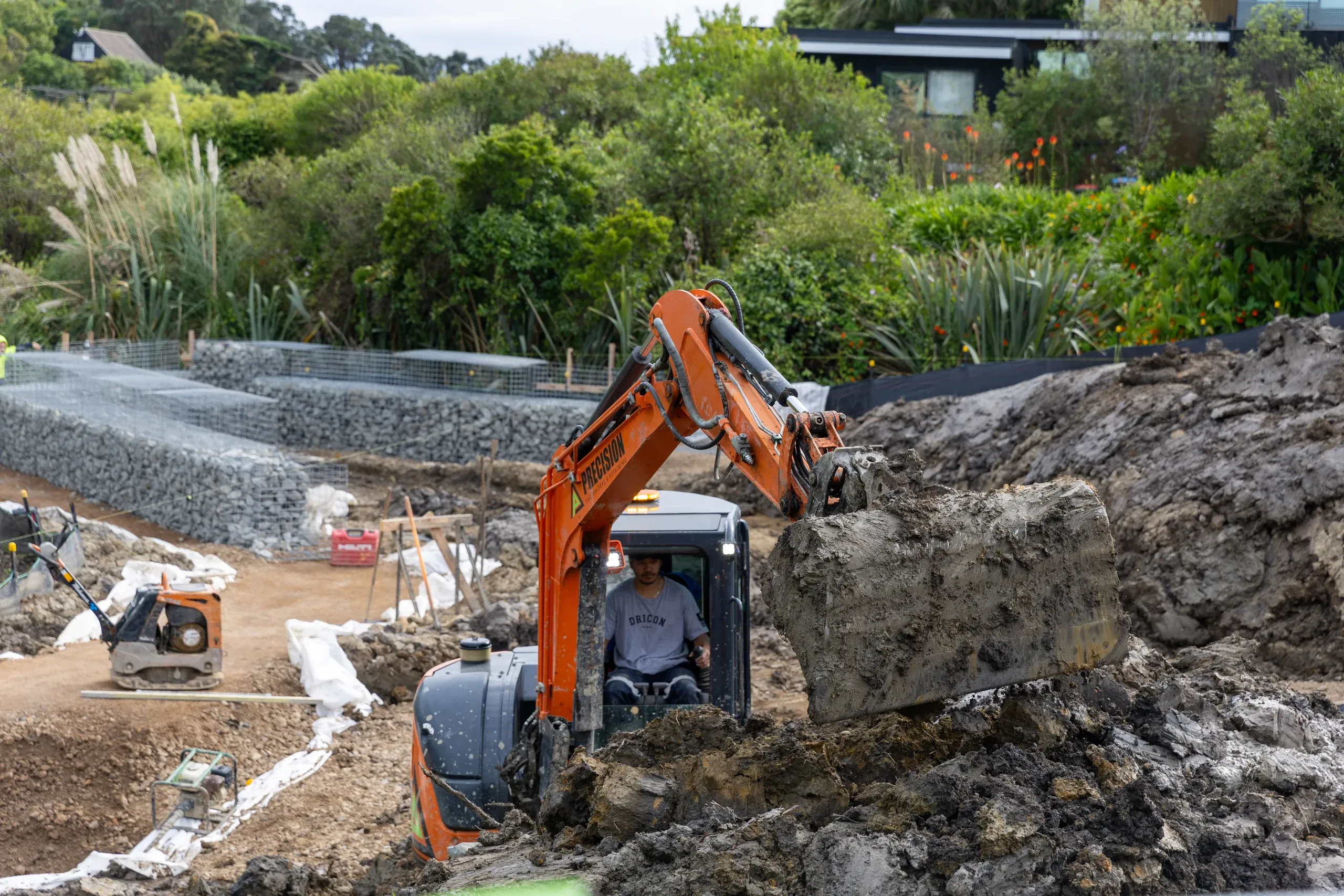 Breaking out rock on the lower terrace, with the first gabion baskets already stacked behind the machine.