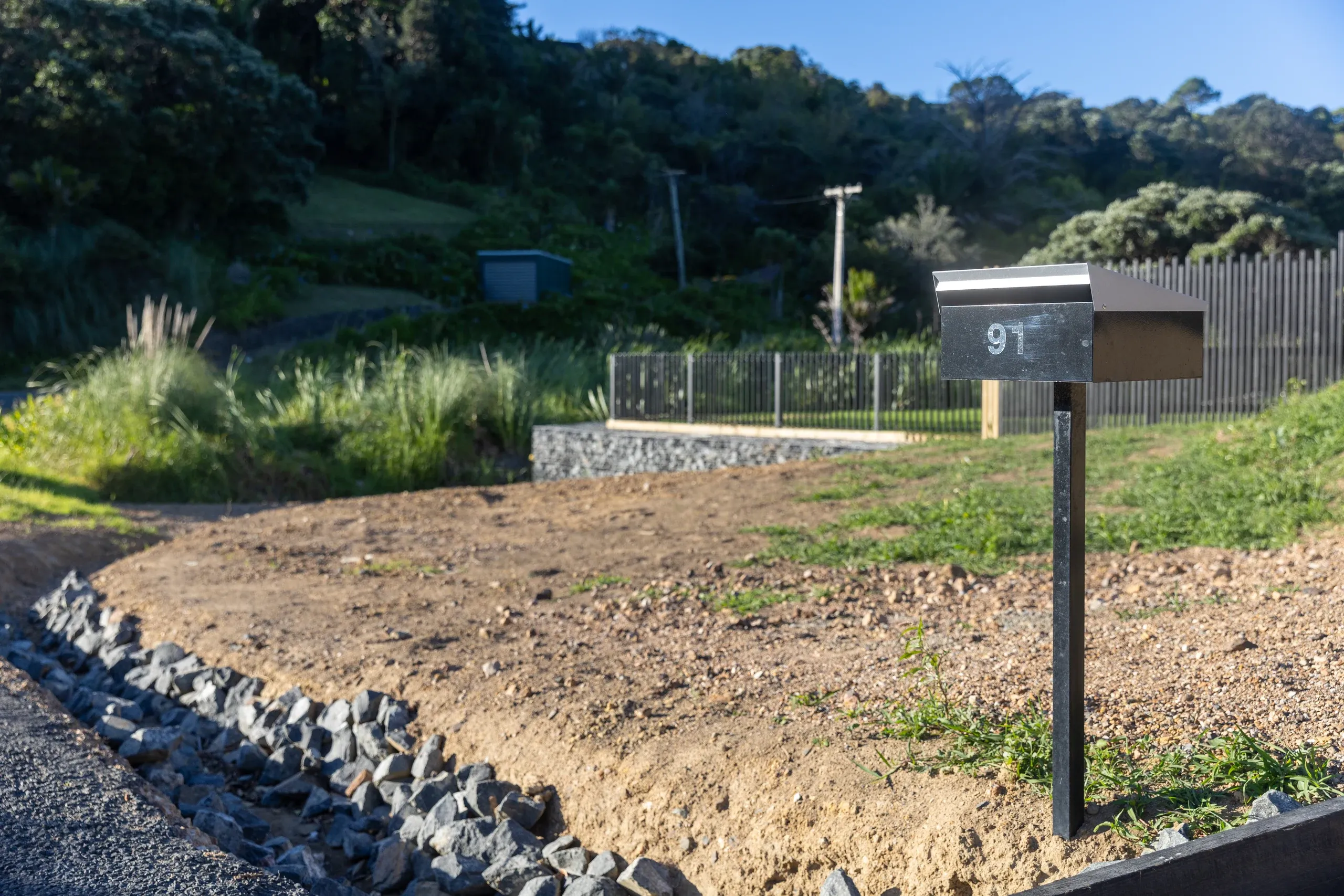 The finished frontage with a rock-lined swale carrying stormwater away from the new driveway.