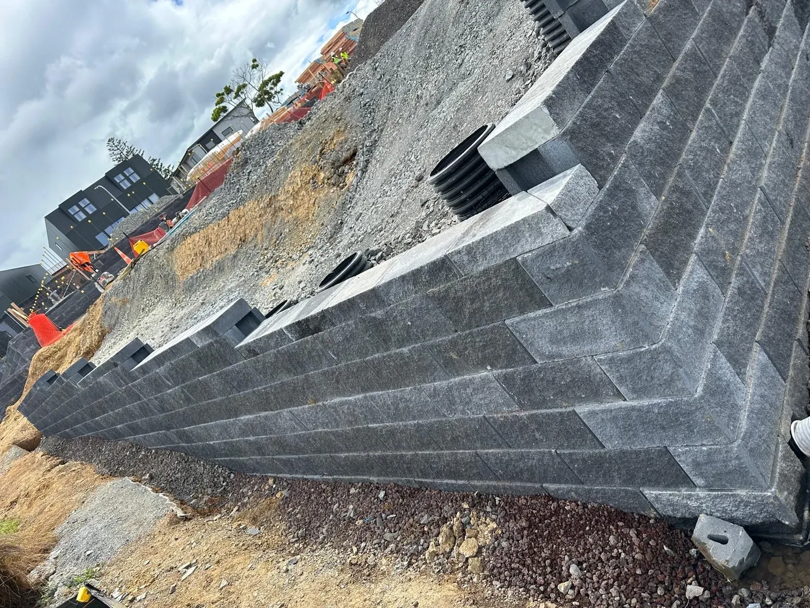 Stepped Keystone block wall seen along its length, with drainage risers set behind the finished face.