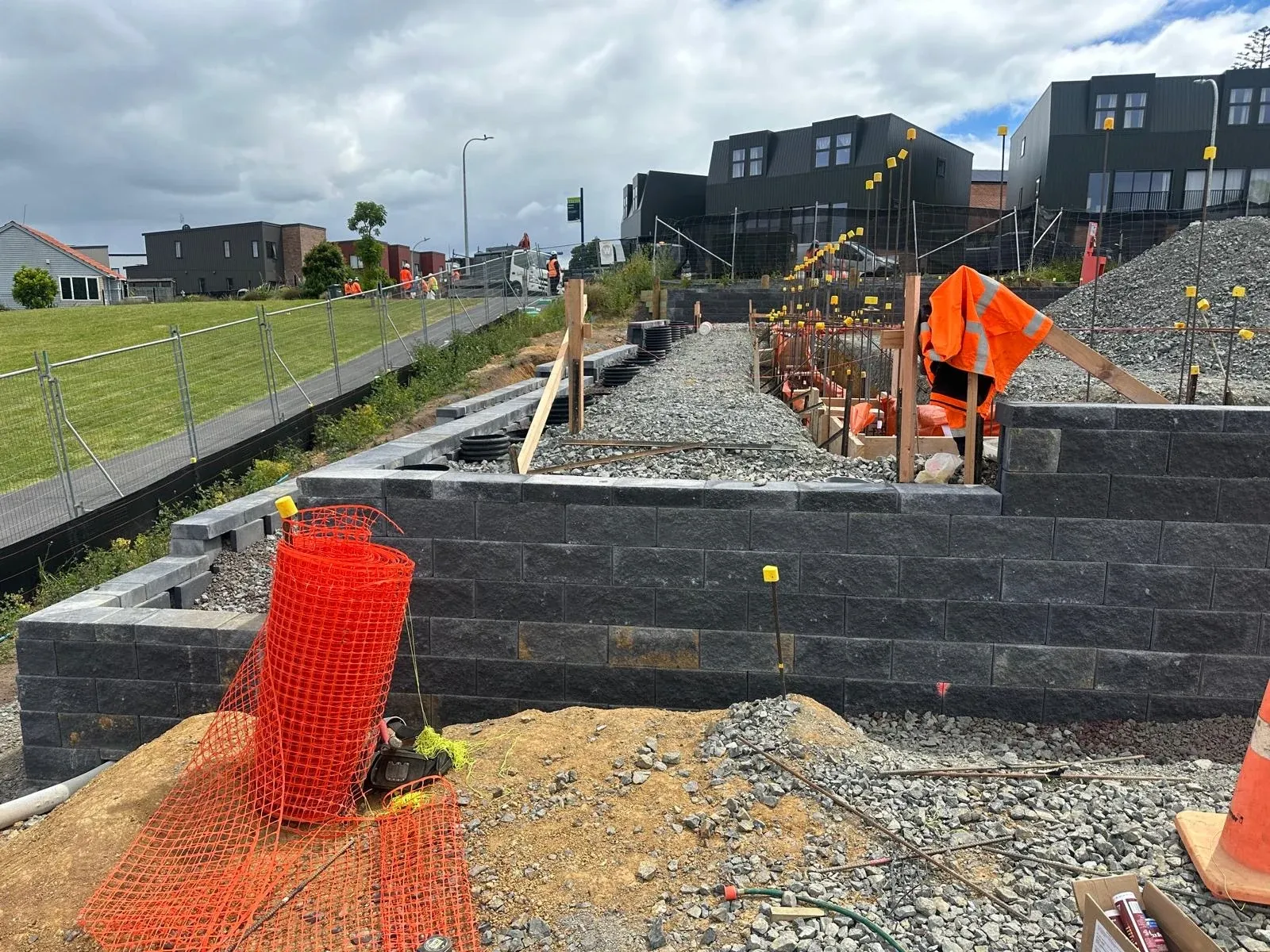 Keystone block wall stepping down in terraces, with completed townhouses on the rise behind.