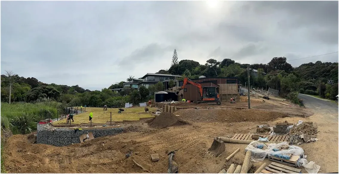 Gabion baskets filled and stacked mid-build, with turf going down on the finished terrace behind.