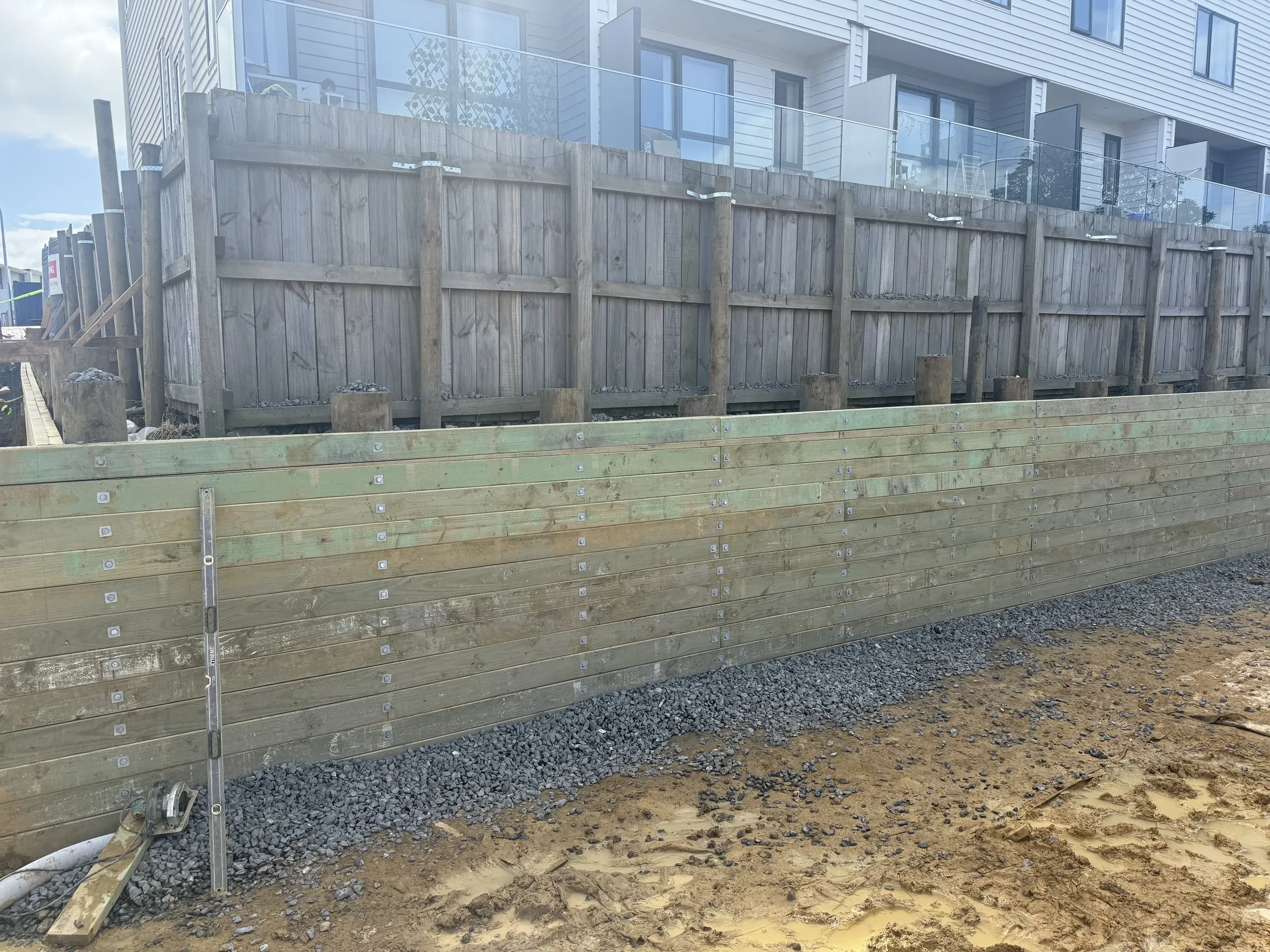 Completed timber retaining wall at full height with drainage metal placed along the base.